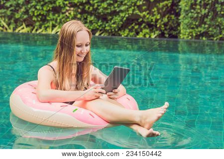 Young Female Freelancer Sitting Near The Pool With Her Laptop In The Hotel Browsing In Her Smartphon