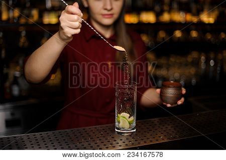Barmaid In A Red Dress Prepares A Mojito In A Crystal Glass, Sprinkling A Brown Sugar Over Slices Of