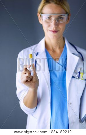 Female medical or research scientist or doctor using looking at a test tube of clear solution in a lab or laboratory.
