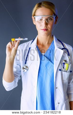 Female medical or research scientist or doctor using looking at a test tube of clear solution in a lab or laboratory.