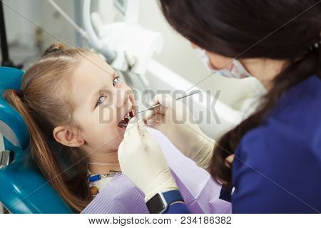 Child Lies In Comfortable Dentis Chair And Goes Through Procedure Without Fear While Female Doctor I