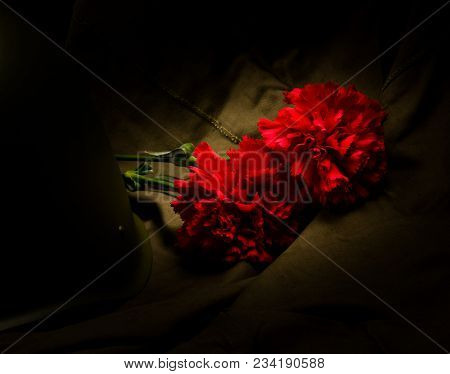 2 Carnations And A Helmet, On A Background Of Military Cloth