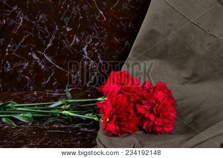 4 Carnations With A Military Cloth, On The Background Of A Memorial Plate