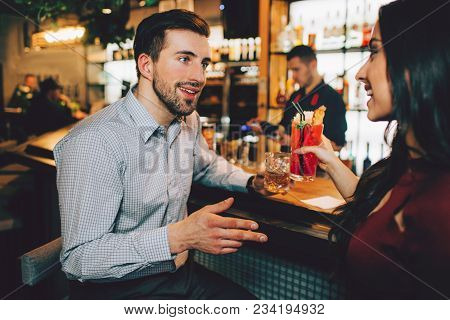 Handsome Man Sitting Close To A Beautiful Girl And Talking To Her. They Are On A Date. She Is Holdin