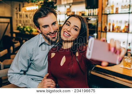 A Picture Where Girl Is Making Selfie With Her Boyfirend. They Are Smiling And Looking To The Camera