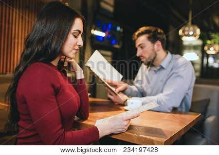 Closer Look To A Stunning Girl Sitting With Her Boyfriend In A Restaurant. Both Of Them Are Looking 