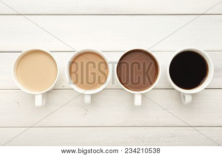 Different Cups Of Coffee On White Wooden Table, Top View. Gradient From Light Americano With Milk To