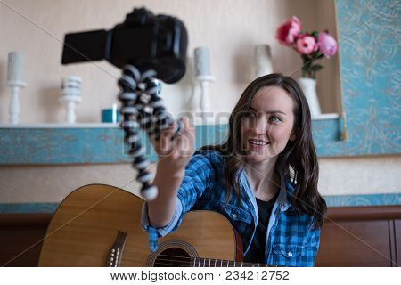 Young Girl With Acoustic Guitar In Bedroom Records Block On Dslr Camera While Holding It In Front Of