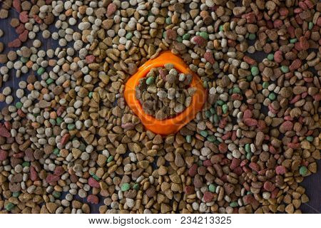 Orange Plastic Bowl Filled With Dry Pet Food Surrounded By Dry Food For Cat And Dogs