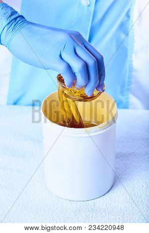 A Pack Of Stretchy Golden Luminous Sugaring Paste With A Hand Taking It
