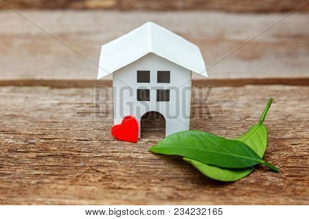 Miniature White Toy Model House With Green Leaves And Red Hearts On Wooden Backgdrop. Eco Village, A