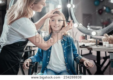 Magnetic Look. Nice Professional Makeup Artist Holding Mascara And Using It While Doing Professional
