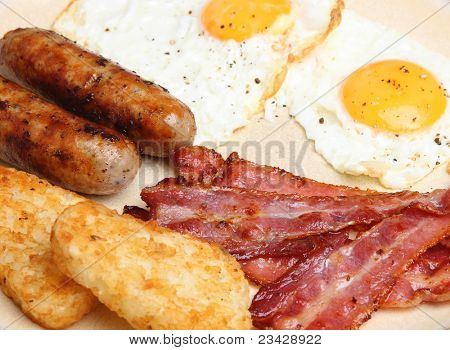 Prima colazione con uova fritte, salsicce, pancetta e frittelle.