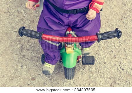 Drop Down View Of Baby Bike Handle. Child Pushing On Pedals.