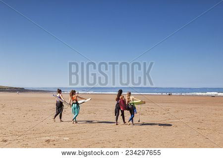 18 June 2017: Croyde Bay, North Devon, England, Uk - Four Young Women Approch The Sea With Surf Boar