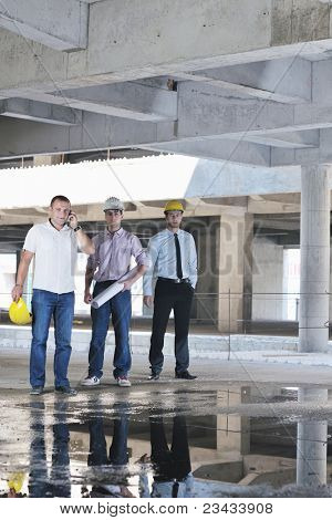 Team liikemiesten ryhmä, arkkitehti ja insinööri construciton päällä tarkistaa asiakirjoja ja b