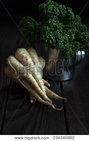 A Bunch Of Roots And Parsley On A Dark Wooden Table