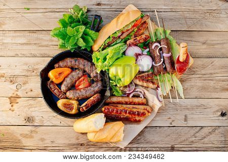 Oktoberfest. Assorted Different Grilled Sausages On A Wooden Table. Fried Sausages On A Cast-iron Fr