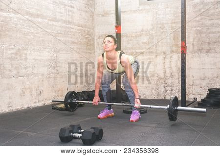 Beautiful Young And Attractive Girl Dead Lift Workout In The Gym With Small Barbell Weights As Worm 