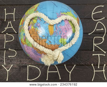 Earth Day Concept. Heart Knoted With Rope Lays On Globe.