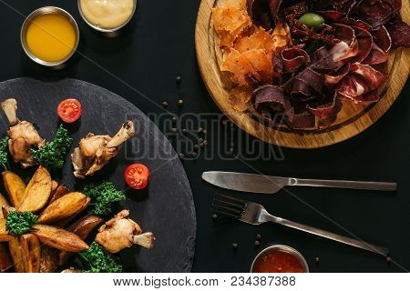 Top View Of Tasty Roasted Potatoes With Chicken And Gourmet Assorted Meat On Black