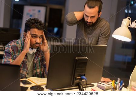 deadline, technology and people concept - creative team with computers working together late at night office