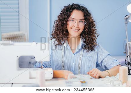 Beautiful Seamstress Looking At Camera And Working With Beads. Fashion Design. Rolls Of Thread