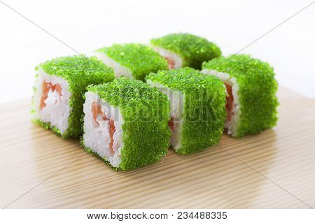 One Set Of California Rolls Covered Green Tobiko Or Masago Caviar On A Wooden Board On A White Backg