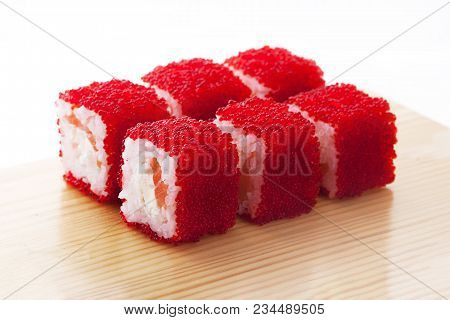One Set Of California Rolls Covered Red Tobiko Or Masago Caviar On A Wooden Board On A White Backgro