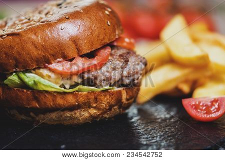 Burger With Cheese And French Fries Or Chips On Darj Stine Table