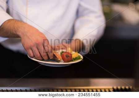 Master chef hands cooking grilled salmon fish with potatoes on a restaurant kitchen