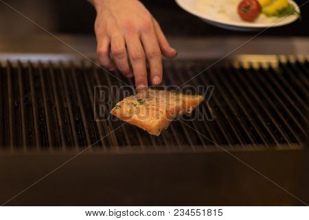 Master chef hands cooking grilled salmon fish with potatoes on a restaurant kitchen