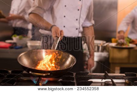 Chef cooking and doing flambe on food in restaurant kitchen