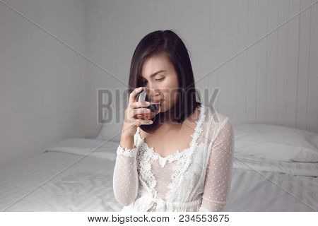 Asian Woman In White Nightgown Drinking Water On The Bed At Bedroom
