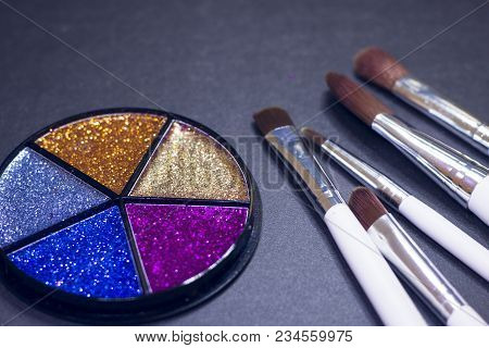 A Palette Of Colorful Glitter Eyeshadow And Profeccional Make Up Brushes On A Black Background, Clos