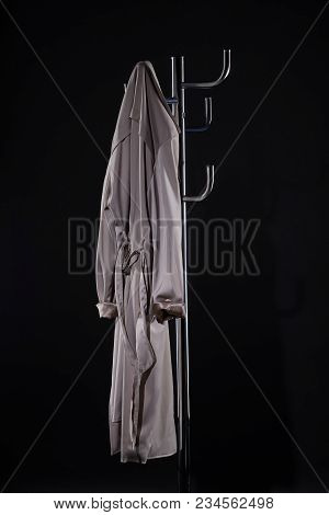 Trench Coat Hanging On Coat Rack Isolated On Black