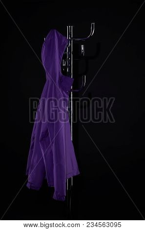 Purple Raincoat Hanging On Coat Rack Isolated On Black