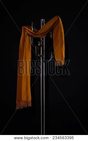 Yellow Scarf Hanging On Coat Rack Isolated On Black