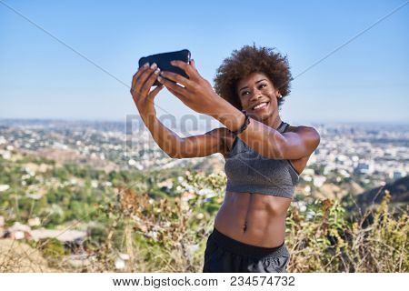fit african american woman taking selfies at runyon canyon with los angeles in background