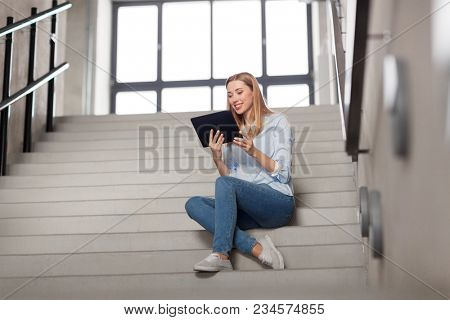 technology, business and corporate concept - happy woman or student with tablet pc computer sitting on stairs