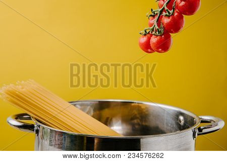 Spaghetti Boiling In Stewpot With Branch Of Cherry Tomatoes Above Isolated On Yellow