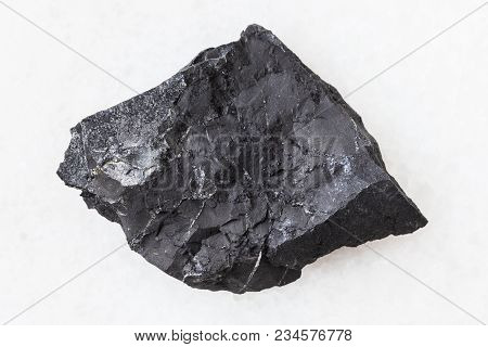 Macro Shooting Of Natural Mineral Rock Specimen - Rough Shungite Shale Stone On White Marble Backgro