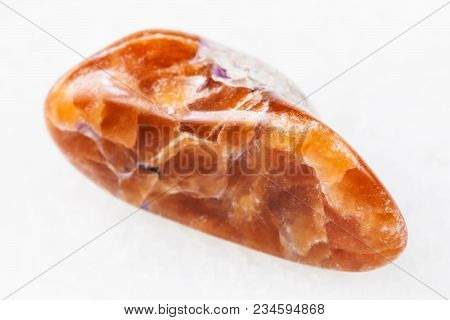 Macro Shooting Of Natural Mineral Rock Specimen - Tumbled Tinaksite Gemstone On White Marble Backgro