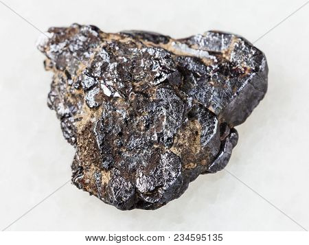 Macro Shooting Of Natural Mineral Rock Specimen - Rough Ilmenite Stone On White Marble Background Fr