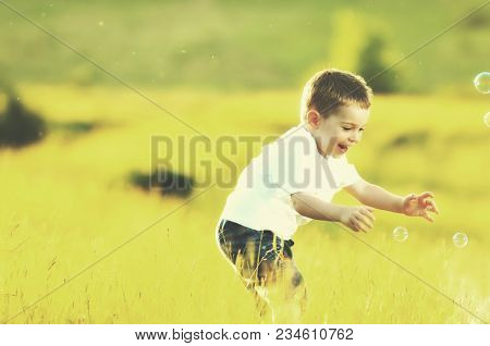 happy young beautiful child have fun on eadow with soap bubbles toy