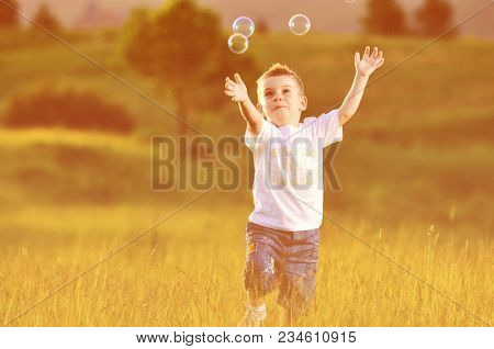 happy young beautiful child have fun on eadow with soap bubbles toy