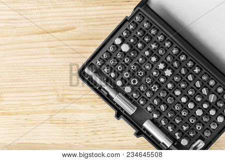 A Set Of Bits For A Screwdriver Of Different Shapes In The Box On A Wooden Surface Close Up. Tool Fo