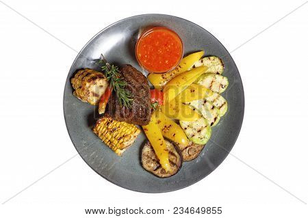 Fried Meat With Garnish Of Pepper, Zucchini, Tomato And Corn With Ajika Sauce Served On A Gray Plate