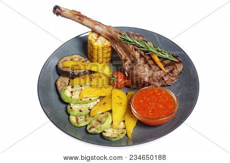 Fried Meat With Garnish Of Pepper, Zucchini, Tomato And Corn With Ajika Sauce Served On A Gray Plate