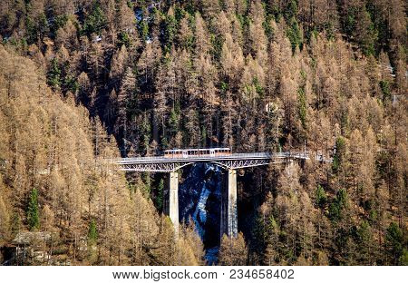 Zermatt, Switzerrland - April 11, 2017: A Red Train Driving Over A An Impressive Bridge In Zermatt